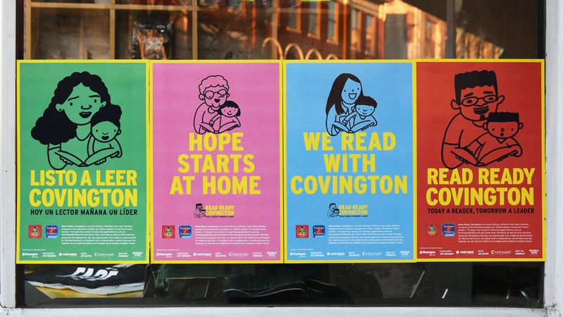 read ready covington posters hung up in a storefront window with bilingual campaign activations